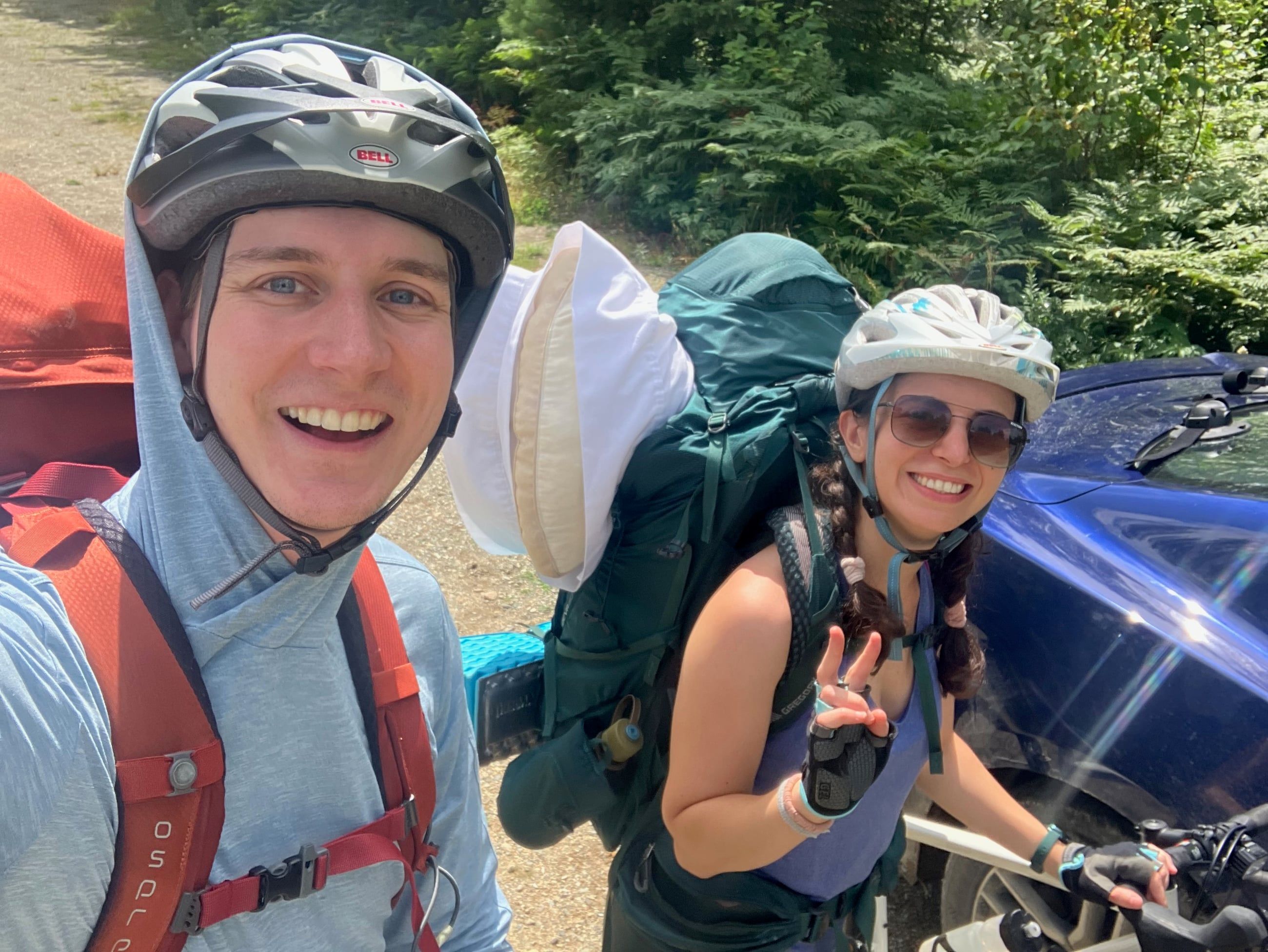 Katherine and Johnny in helmets with loaded bikes on a bikepacking trip