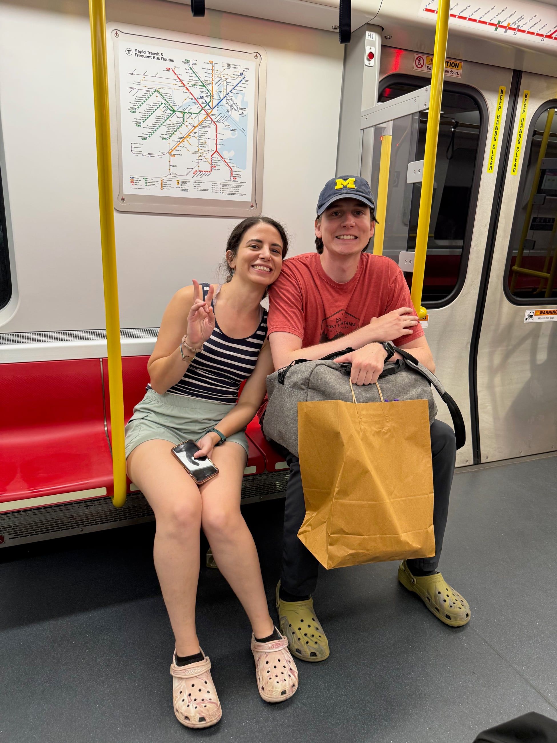 Katherine and Johnny sitting on a train, both wearing Crocs