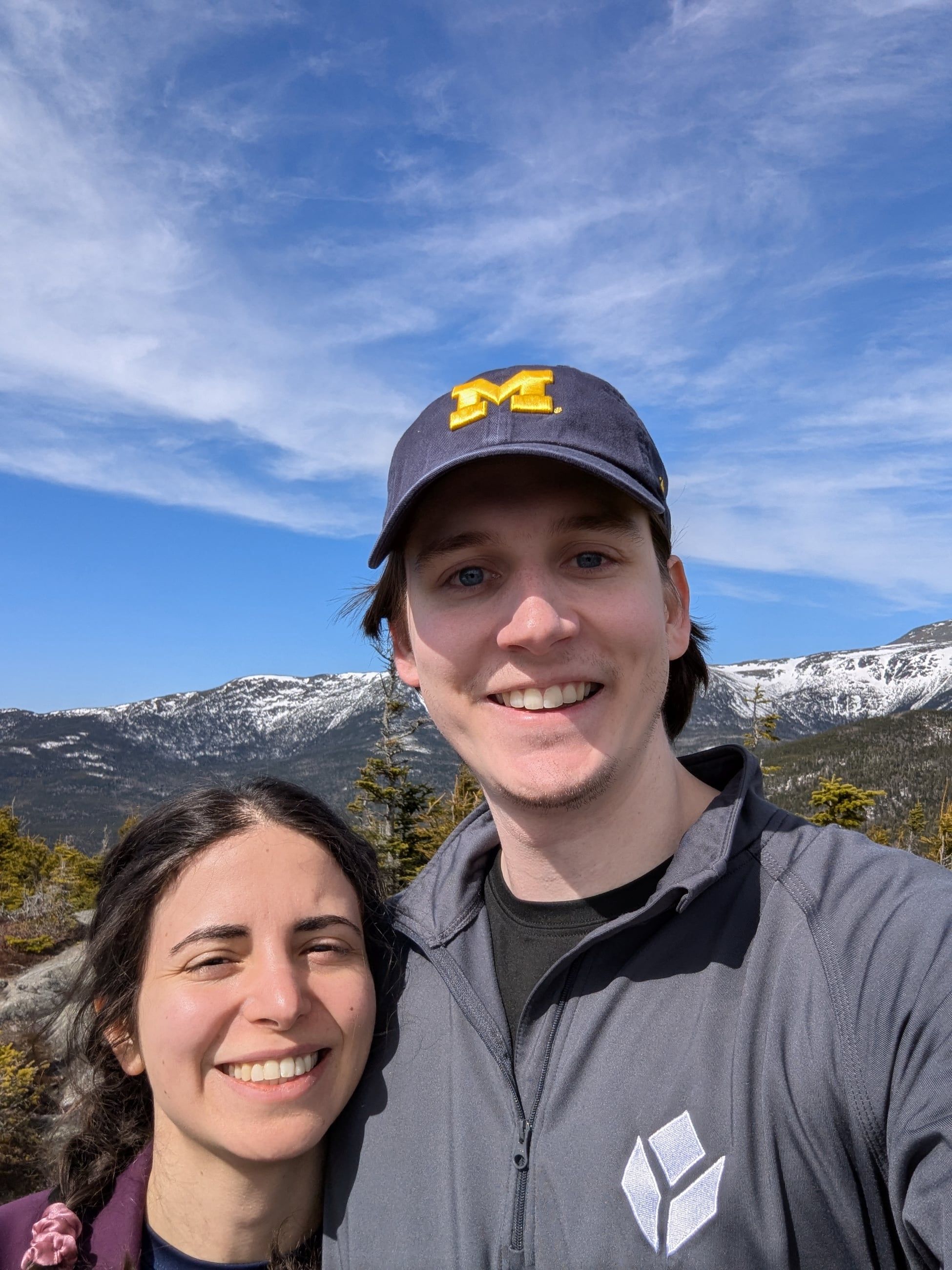 Katherine and Johnny on a ridge with snow-streaked mountains behind