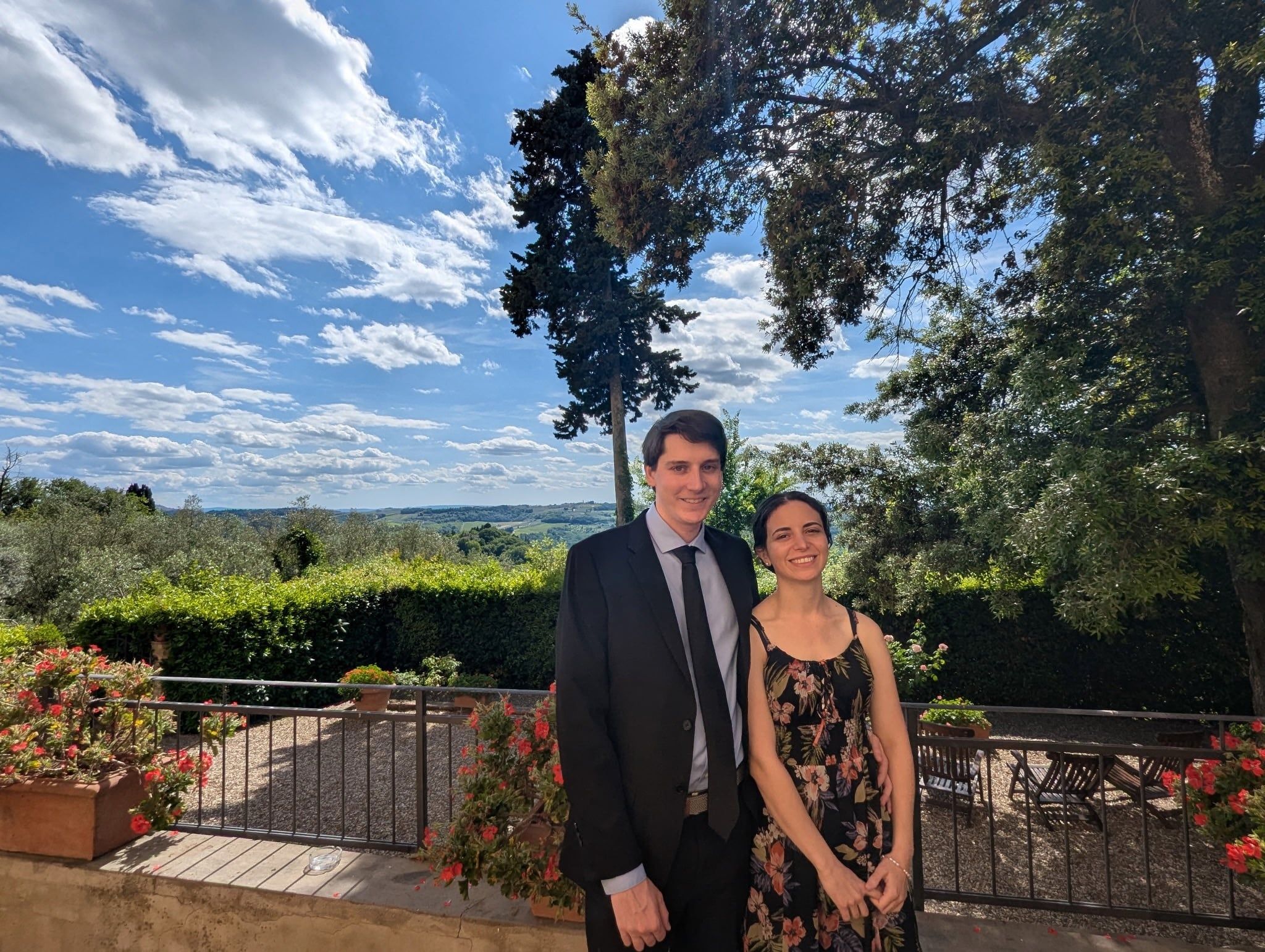 Katherine and Johnny dressed for a wedding on a terrace above the Tuscan hills