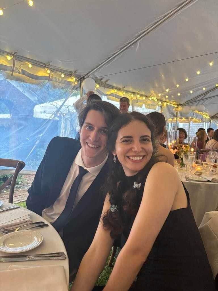 Katherine and Johnny at a table under a string-lit tent, cheek to cheek