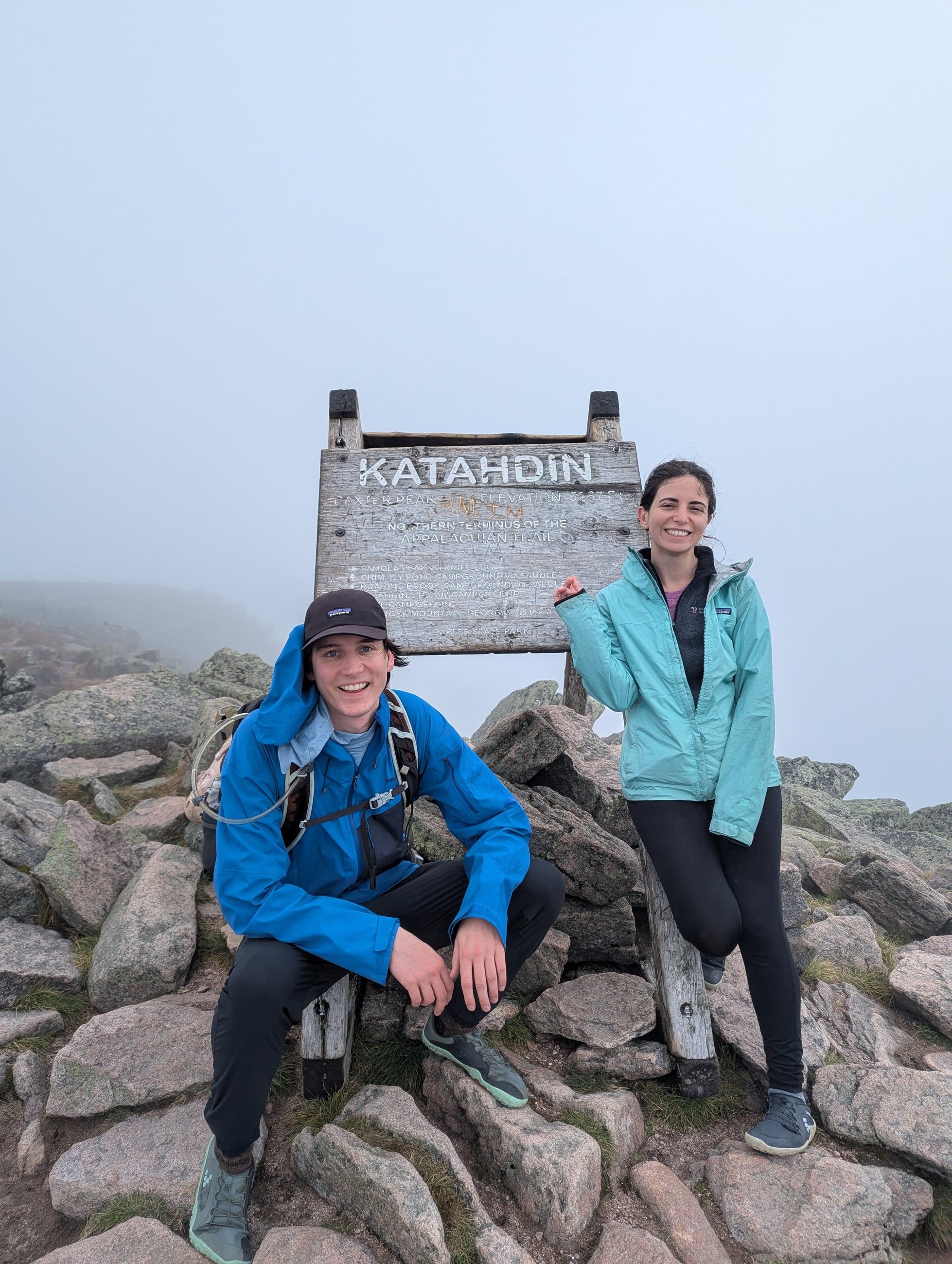 Katherine and Johnny at the summit sign on Katahdin, fog behind them