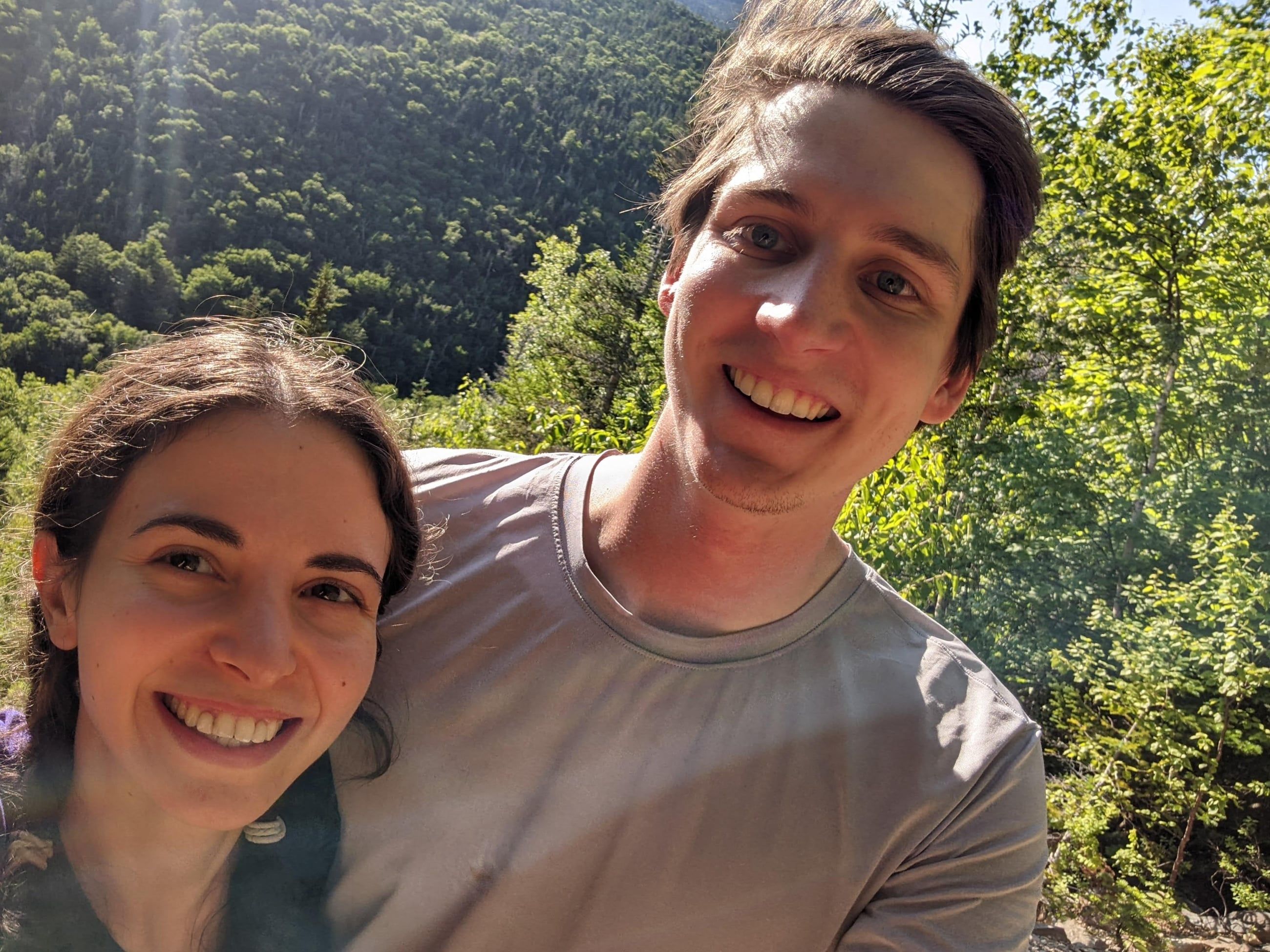 A sunlit selfie of Katherine and Johnny on a green hillside
